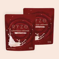 RYZE peppermint mocha superfood creamer packets with milk splash on deep red background